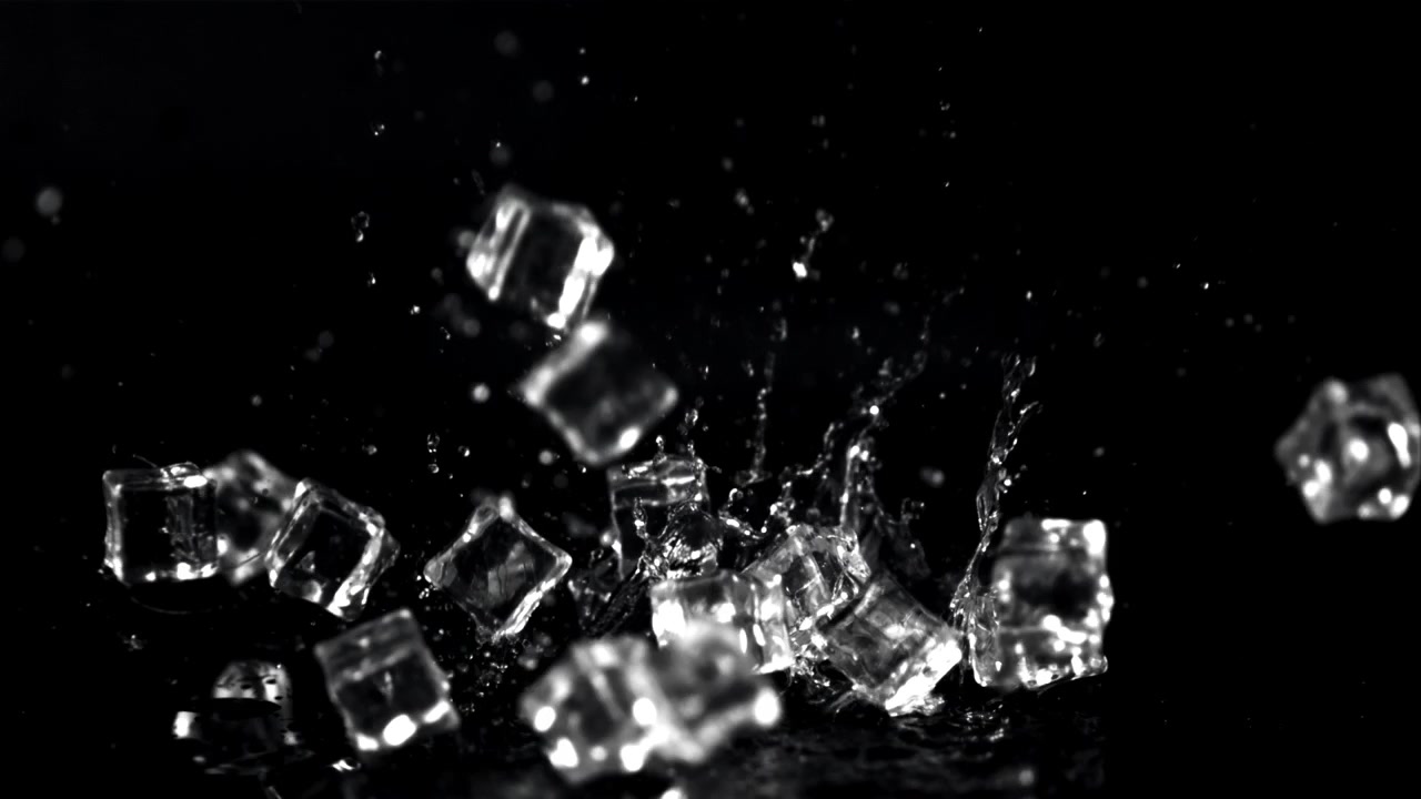 Movimento rallentato: cubetti di ghiaccio che cadono e schizzano su sfondo nero