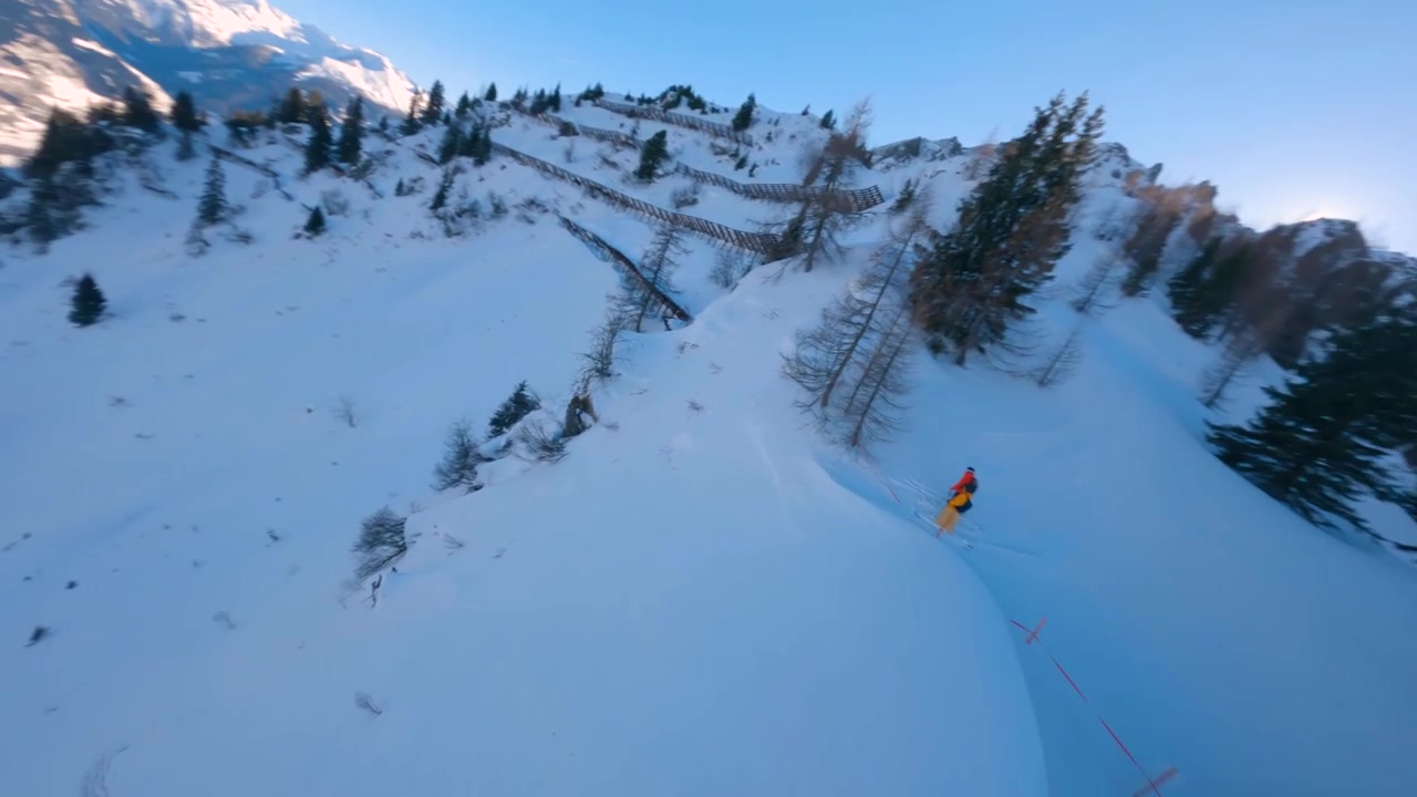 Drone FPV che riprende due sciatori in attesa sulla cresta per scendere una splendida linea di neve fresca nelle montagne invernali austriache.