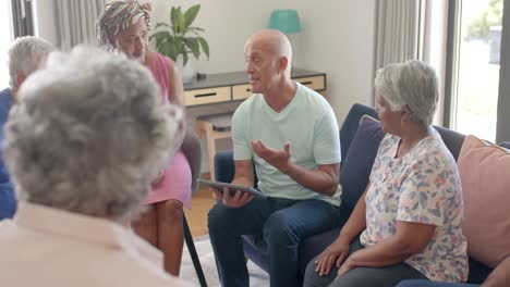 Diversos-Ancianos-Y-Terapeuta-Masculino-Con-Tableta-Hablando-En-Sesión-De-Terapia,-Inalterado,-Cámara-Lenta