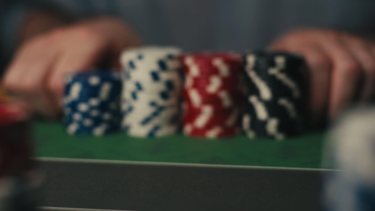 Stacks of colorful poker chips on a table with blurred hands in the background