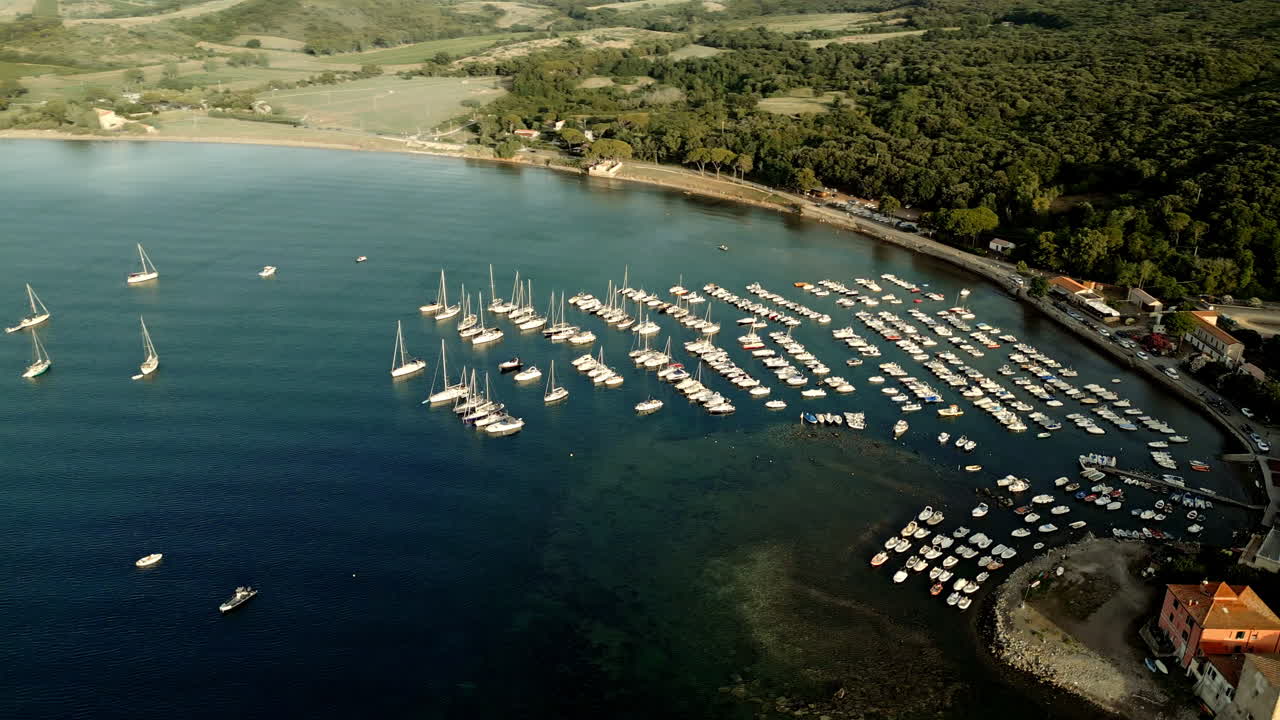 Spiaggia toscana e moli del porto turistico con file di yacht, Italia, aerea