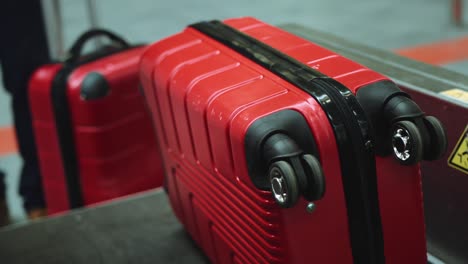 two red luggage suitcases putting on line to weigh in airport. cinematic shot on red camera.