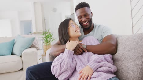 portrait of happy diverse couple embracing in living room