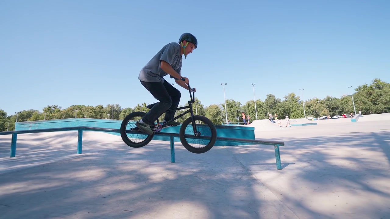 Giovane uomo esegue un trick grind in BMX su un rail allo skatepark