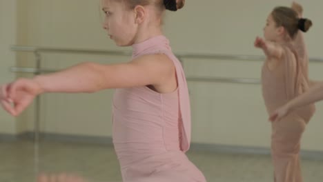 un grupo de jóvenes estudiantes de ballet con ropa de baile negra practicando posiciones en un amplio estudio de ballet con pisos de madera y barras montadas en la pared. expresiones enfocadas y movimientos sincronizados.