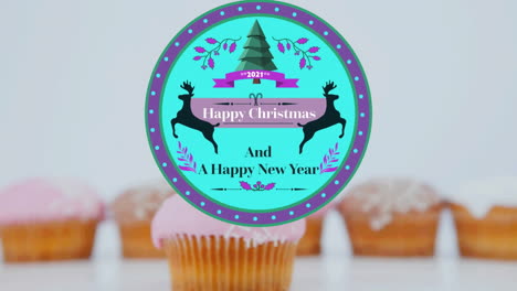 animation of christmas greetings on tag over cupcakes on white background