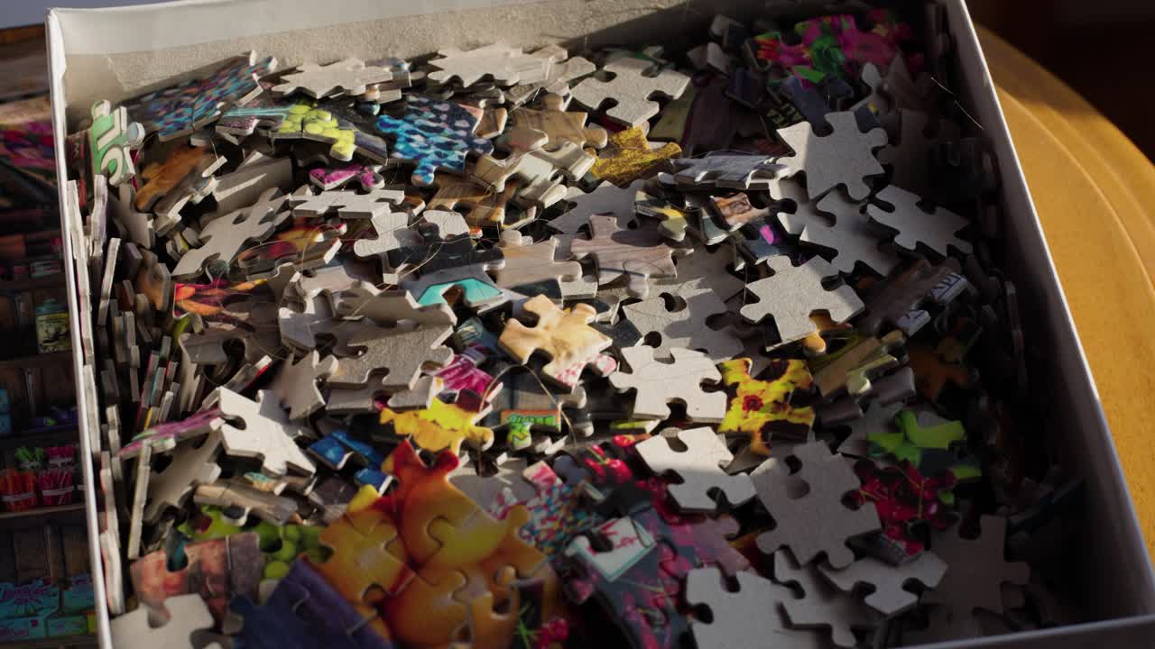 Jigsaw Puzzle pieces in their box in morning light. Handheld slowmo.