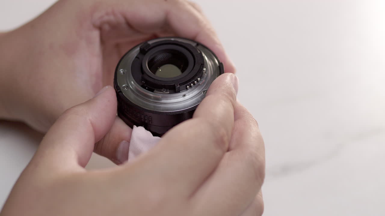 Close-up of an individual holding a camera lens while checking it thoroughly in her hands.