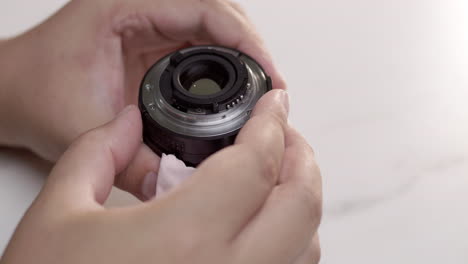 close-up of an individual holding a camera lens while checking it thoroughly in her hands.