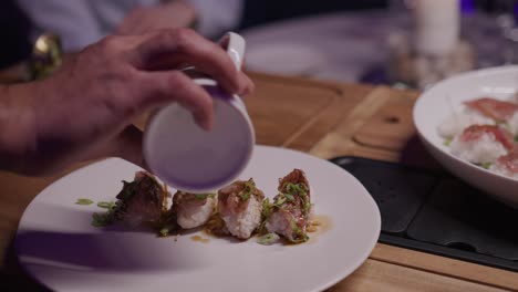 providing table-side service, a waiter pours a luscious stream of what appears to be soy sauce onto wagyu sushi