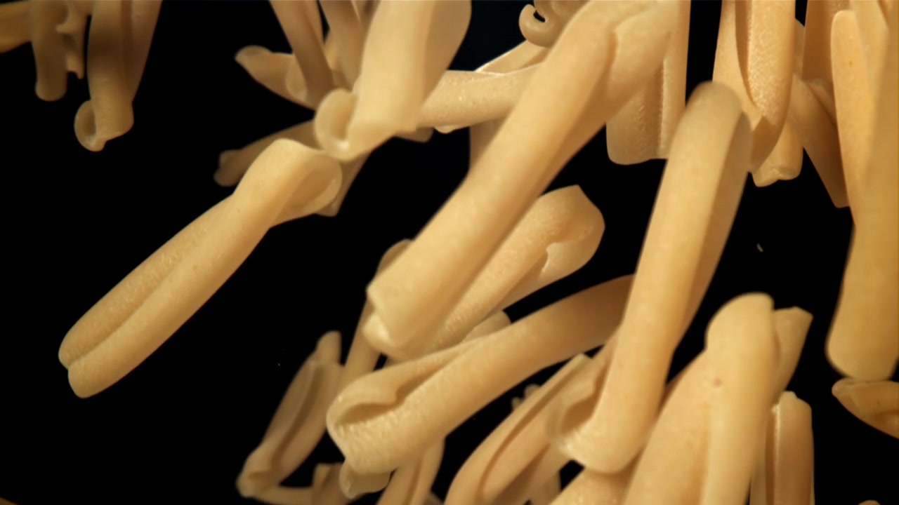 Pasta casarecce che cadono in movimento rallentato su sfondo nero