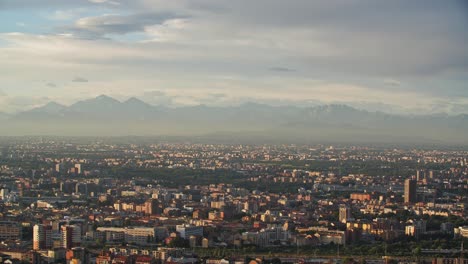 milan cityscape during golden sunset and foggy mountains in horizon, view from above