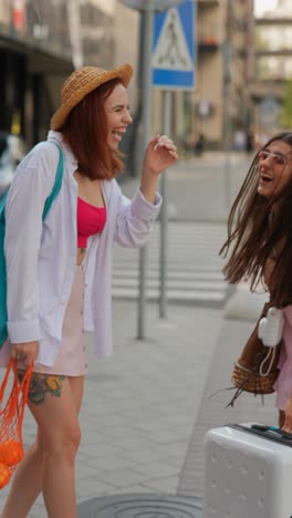 two young women on a city street, traveling, talking and laughing