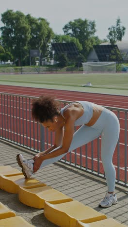 mujer estirándose en un estadio