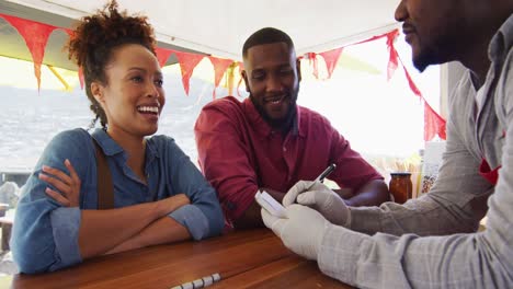 African-american-man-wearing-apron-taking-order-from-a-couple-at-the-food-truck