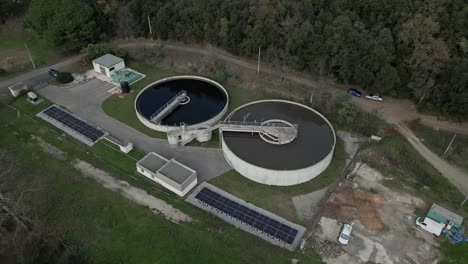 aerial view of wastewater treatment plant featuring circular clarifiers, solar panels, nestled within surrounding woodland landscape in amelie les bains, france