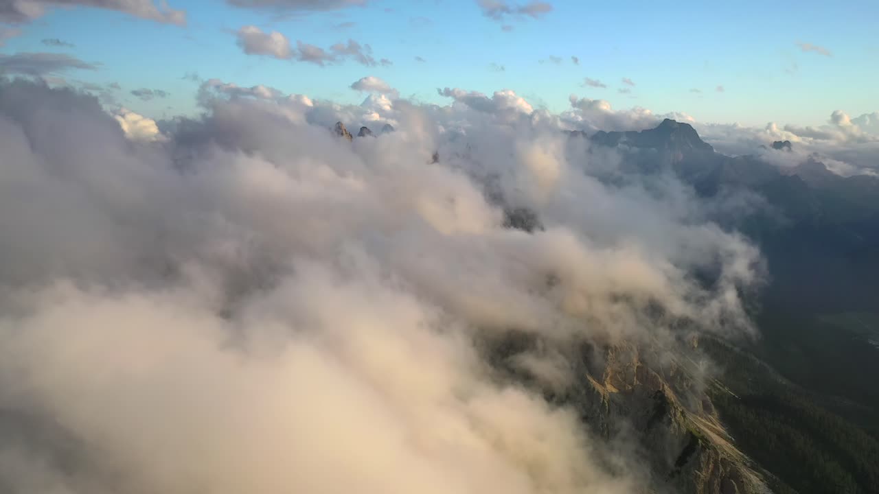 Clouds moving above the Dolomites mountain landscape at sunset, static aerial