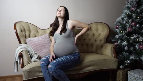 mujer caucásica embarazada siente dolor en la parte inferior de la espalda durante la celebración de navidad
