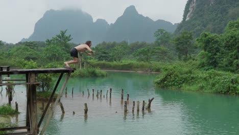man doing backflips from a cliff into a lake