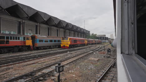 Looking-out-Train-Window-Leaving-Station-in-Bangkok,-Thailand