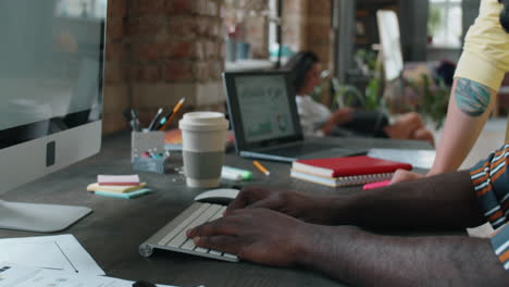 homme afro-américain utilisant un ordinateur et parlant avec un collègue caucasien au travail