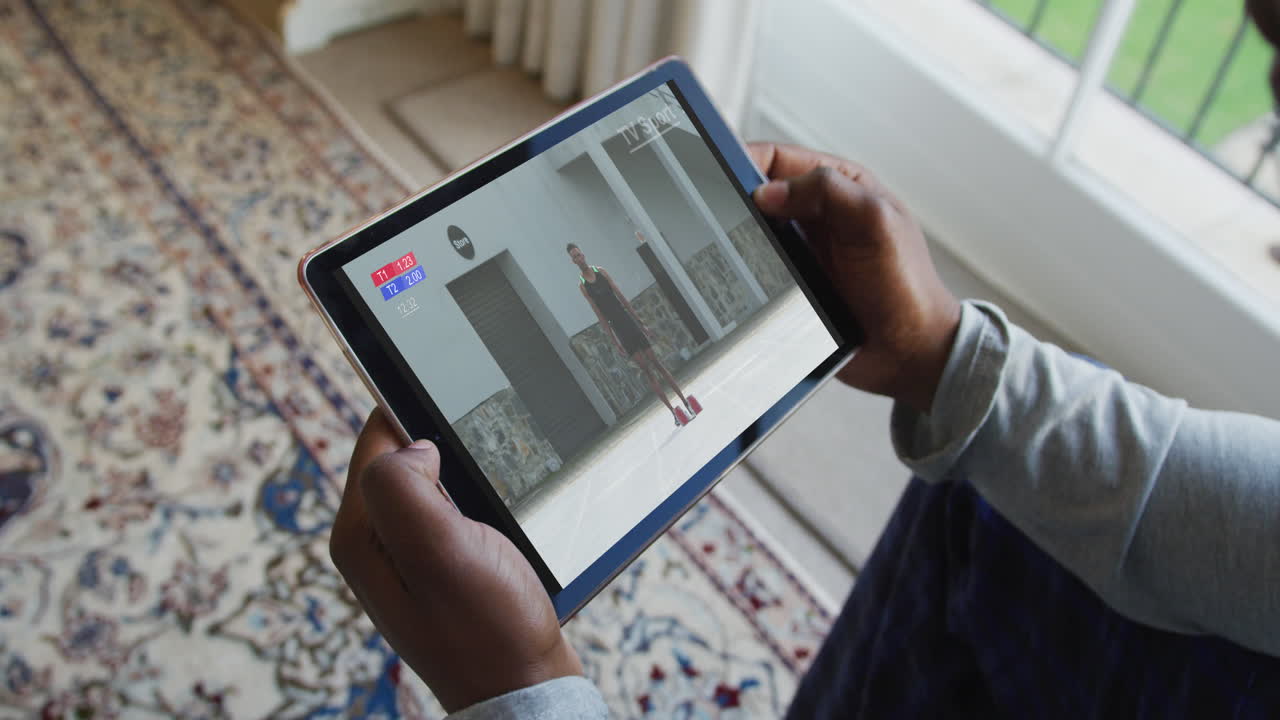 Composite of man sitting at home, watching athletics event on tablet