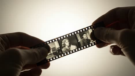 a close-up view of hands holding a film strip featuring vintage black and white portraits, highlighting the artistry and importance of photographic history and nostalgia