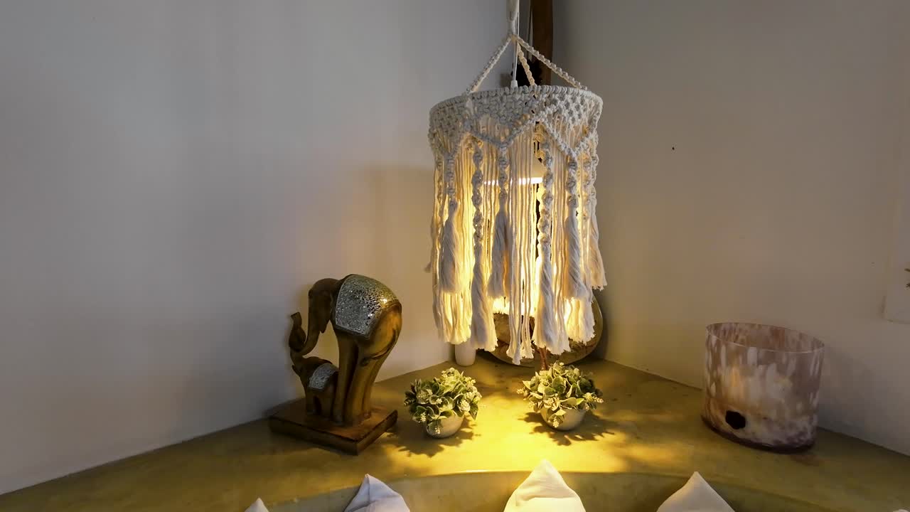 Peaceful scene. Cozy corner with macrame hanging lamp, white walls, decorative pillows, elephant sculpture