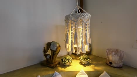 peaceful scene. cozy corner with macrame hanging lamp, white walls, decorative pillows, elephant sculpture