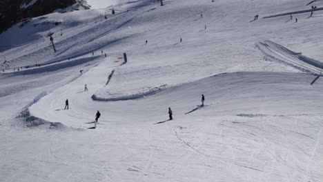 Aerial-birds-eye-shot-of-skier-skiing-down-curvy-slope-of-snowy-mountain-in-sunlight