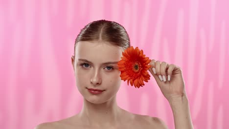 young woman with bright orange flower on vibrant background a serene moment of a woman enjoying the scent of a vibrant orange flower eyes closed in relaxation