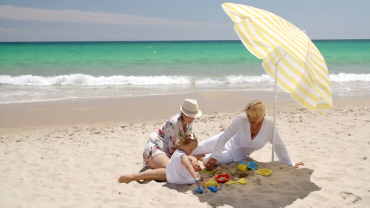 nonna, mamma e la bambina giocano sulla spiaggia.