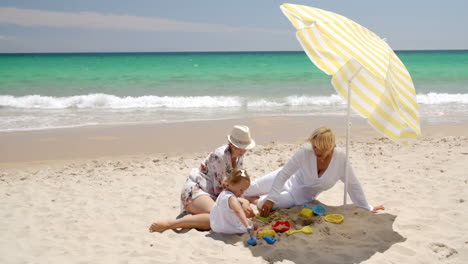 Oma-Und-Kleines-Mädchen-Spielen-Im-Strandsand