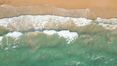 overhead drone flight over beautiful beach with turquoise waters and people swimming