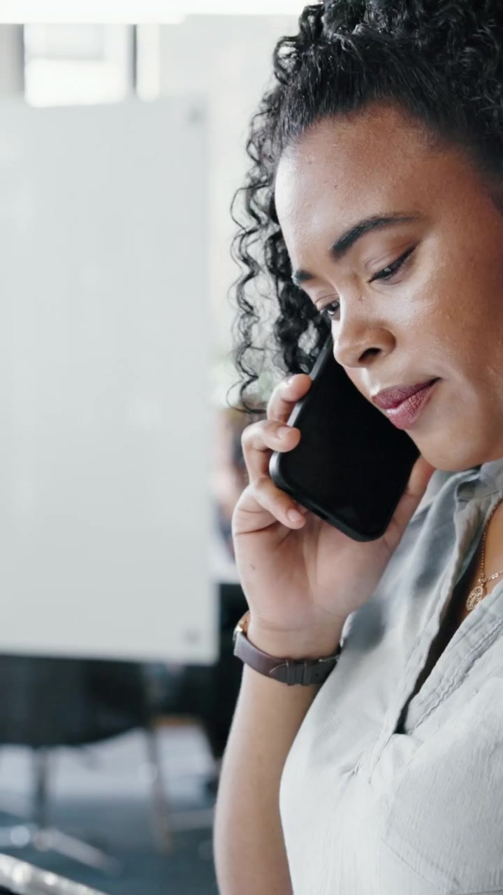 Professional Woman Talking on Smartphone While Reviewing Tablet in Office