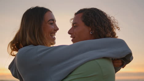 una pareja abrazándose en la playa al atardecer.