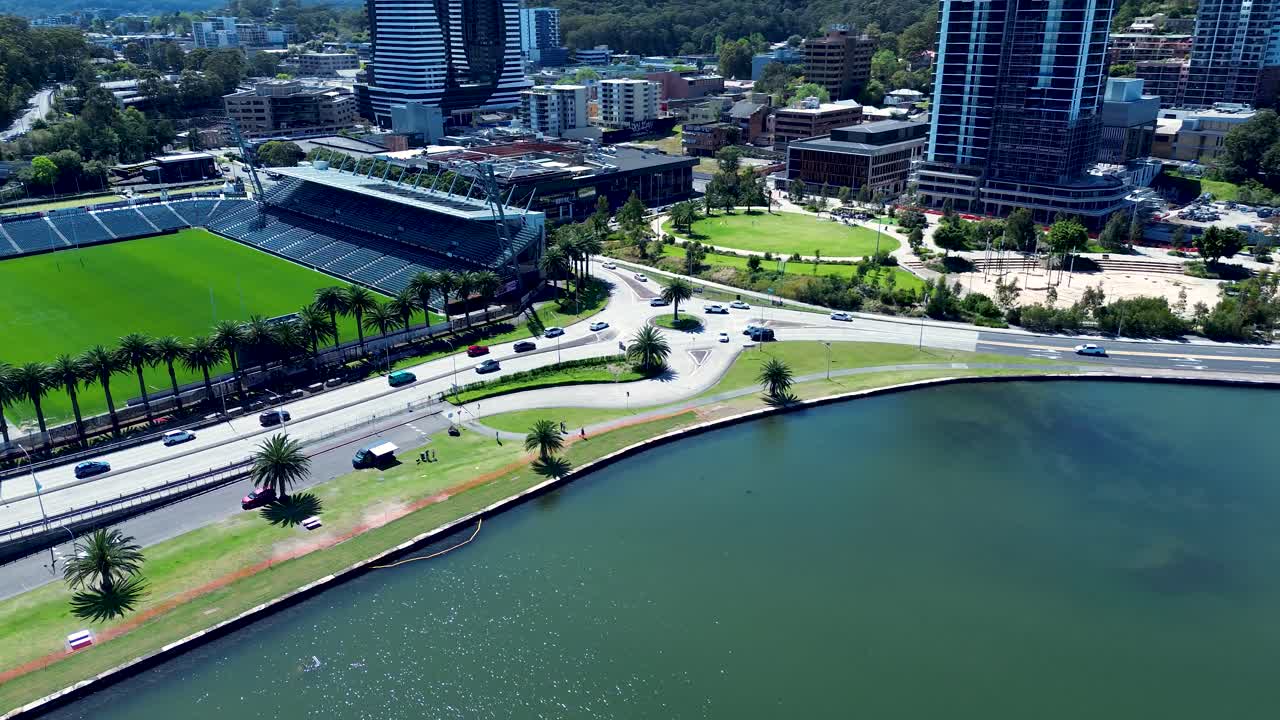 Drone aerial landscape of car vehicles driving along main road around urban CBD centre of Gosford city with waterfront foreshore and sports stadium in Central Coast tourism Australia transport travel