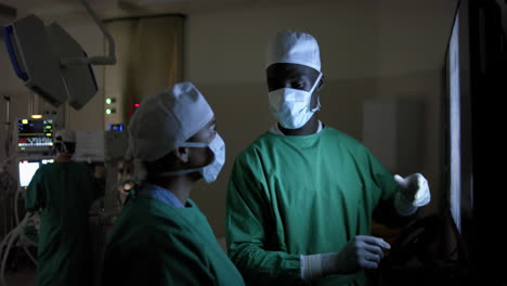 diverse surgeons discussing with x-ray scans in operating theatre at hospital, slow motion