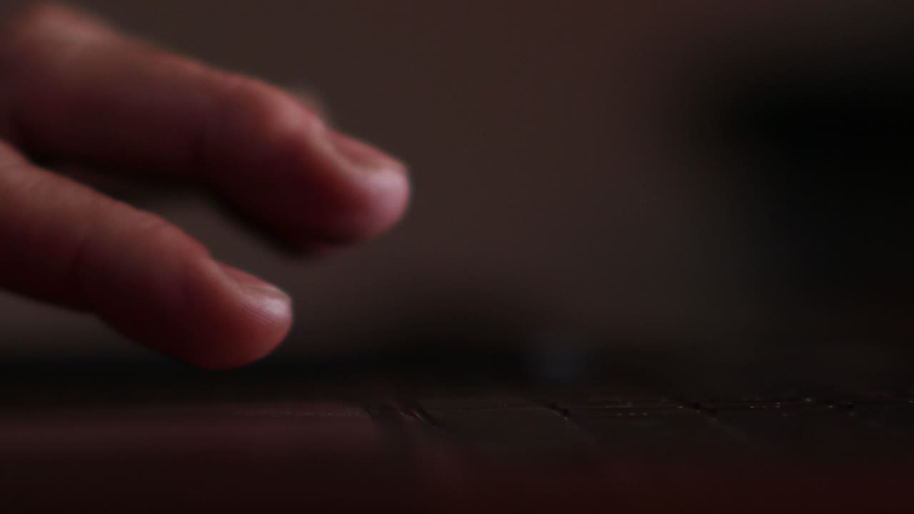 Close up of man's fingers scrolling and tapping the track pad of a laptop backlit by the screen