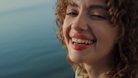 Closeup-face-happy-girl-in-front-blue-ocean.-Curly-lady-smiling-looking-camera.