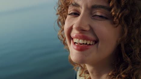 closeup face happy girl in front blue ocean. curly lady smiling looking camera.