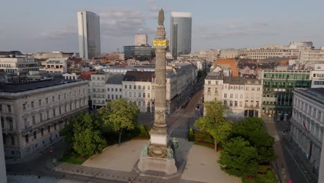 Drone-Aéreo-Sobre-La-Histórica-Colonne-Du-Congres-En-El-Parque-Urbano-De-Bruselas-Bélgica-Al-Aire-Libre-Horizonte-De-Verano-En-Una-Plaza-Cuadrada,-Estableciendo-Una-Ubicación-De-Luz-Natural