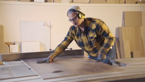 adult carpenter cuts wood in the carpentry shop.