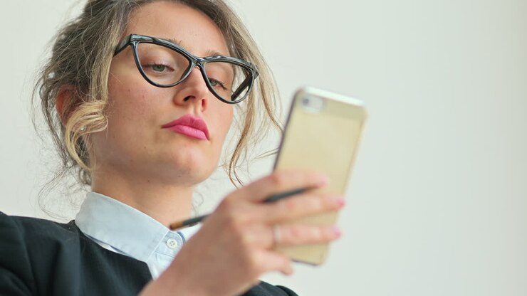 Primo piano di una professionista con gli occhiali mentre digita al telefono