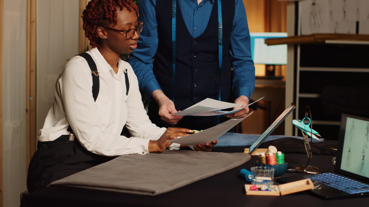 Tailor and apprentice reviewing sketches