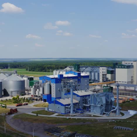 modern agricultural factory on field. warehouse granary aluminum containers for storing loose grain. elevators. large granary in summer. aerial view.