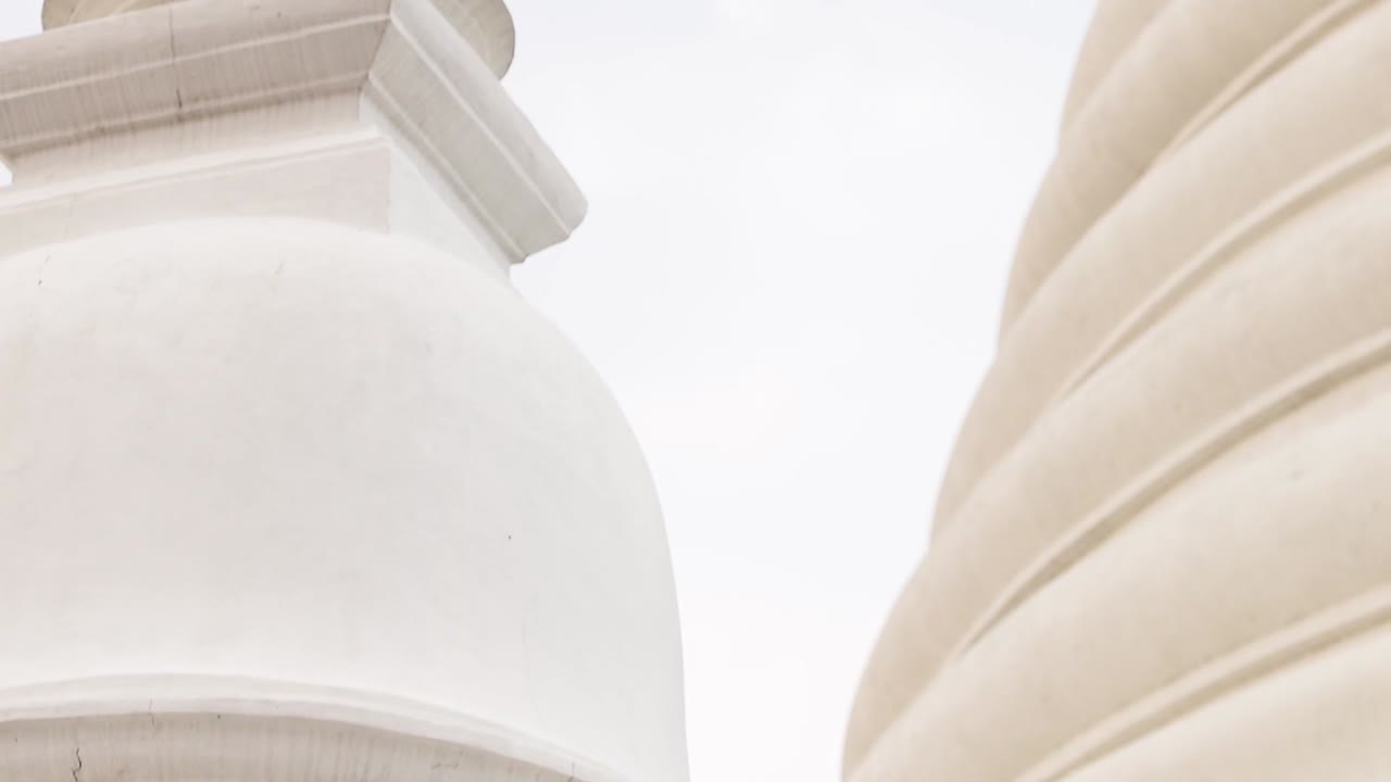 Detailed view of a white pagoda's spire and architectural elements against a cloudy sky.