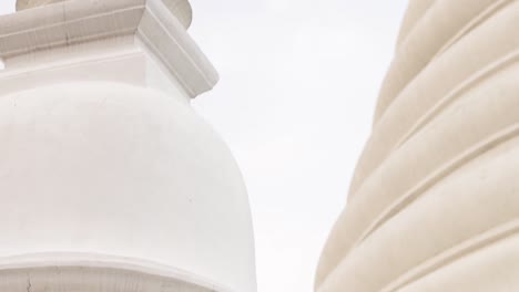 detailed view of a white pagoda's spire and architectural elements against a cloudy sky.