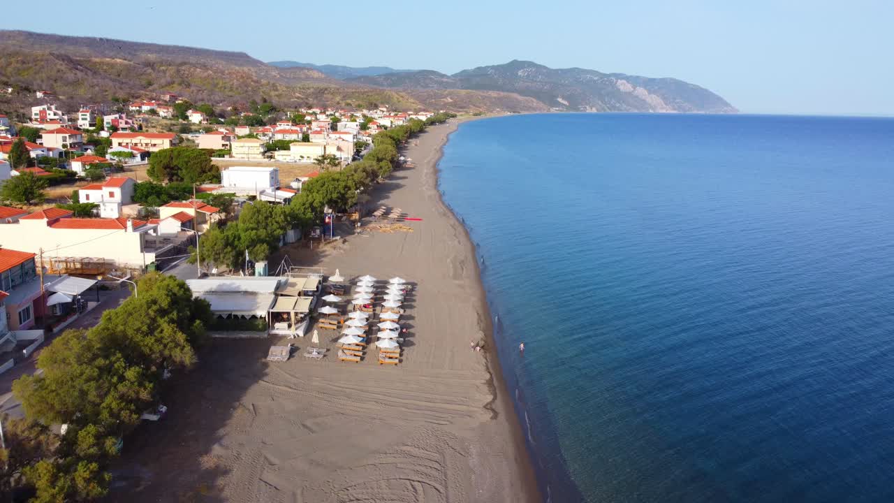 Greek Island Vatera beachside lounging areas, local tavernas, cafes, hotels, bar and restaurant buildings surrounded by mountains and sea, Lesvos Island, Drone shot