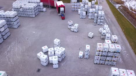 forklift truck driver in warehouse driving between rows of shelving with stacks of boxes and packaging materials